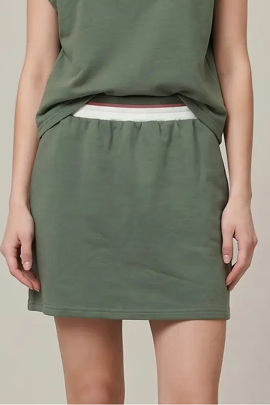 Woman wearing a green dress with a white collar against a beige background